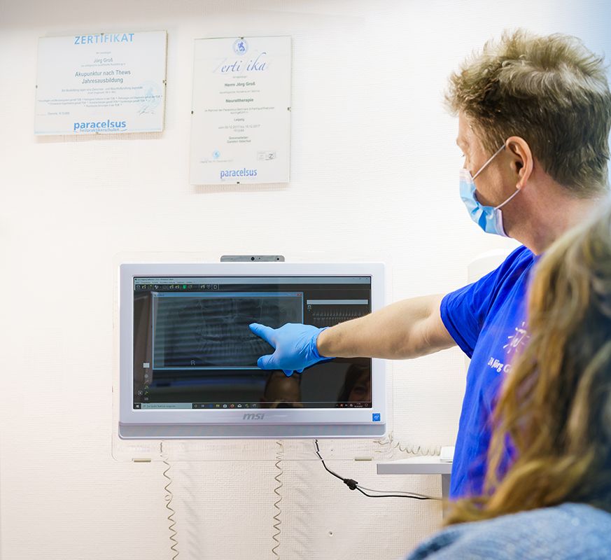 Zahnarzt Jörg Groß erklärt einer Patientin ihre Röntgenaufnahme am Bildschirm